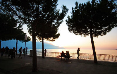Silhouette people on beach against sky during sunset