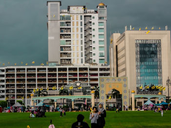 People in front of buildings in city against sky