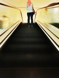 Woman standing on escalator