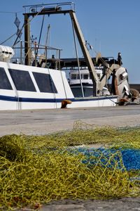 Fishing boats moored at harbor against clear sky