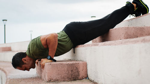 Man doing push up on the step outdoor during rainy day