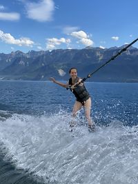 Full length of young woman in sea against mountains