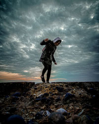 Full length of man standing on rock at beach against sky