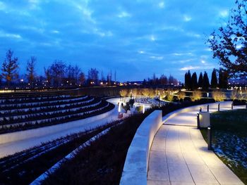 Footpath in park against sky at dusk