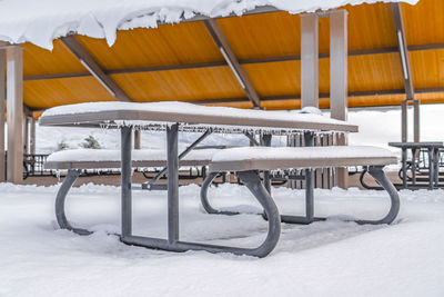 Empty chairs and tables on snow covered land