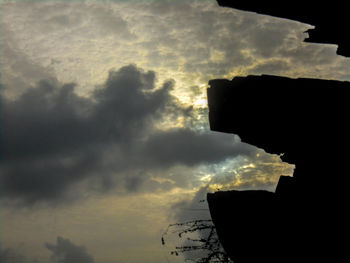 Low angle view of silhouette buildings against cloudy sky