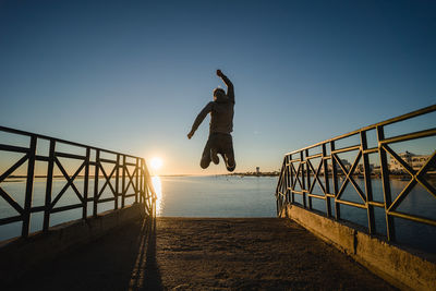 Man jumping on sea against clear sky