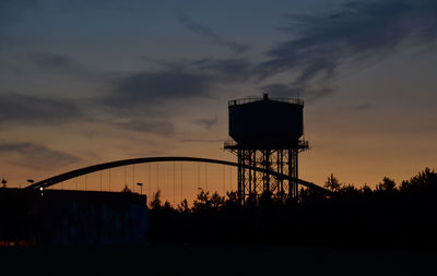 Silhouette water tower against sky at sunset