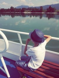 Rear view of woman sitting on boat in lake