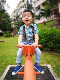 Full length of cute baby boy sitting on seesaw at playground