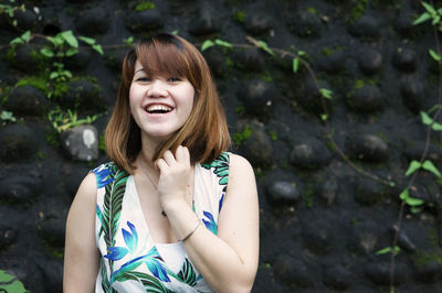 Portrait of beautiful woman laughing while standing against wall