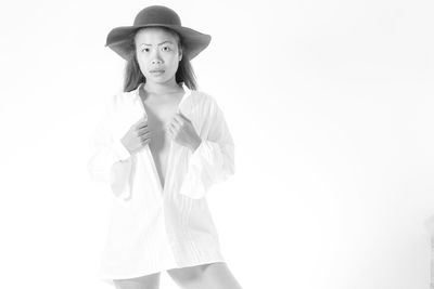 Portrait of young woman standing against white background