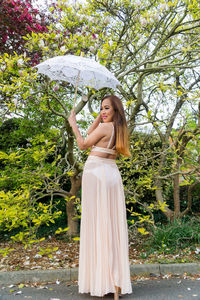 Young woman standing against tree