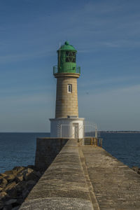 Lighthouse by sea against sky