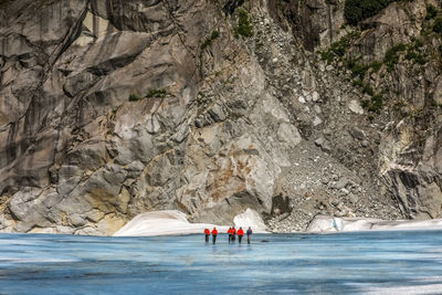 People on rocky mountain by sea