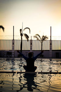 Rear view of silhouette woman by swimming pool against sky