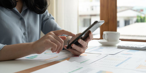 Midsection of woman using mobile phone on table