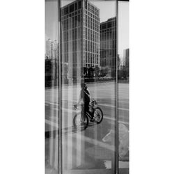 Man riding bicycle on glass building