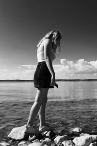 Woman standing at beach against sky