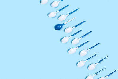 Concept of white plastic spoons on blue background. flat lay, top view, copy space.