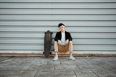 Woman sitting on chair against wall