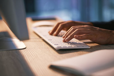 Cropped hand of woman using laptop on table