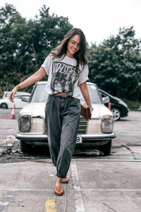 Portrait of woman standing by car in city