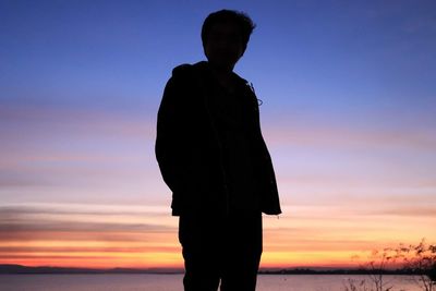 Silhouette man standing at beach during sunset