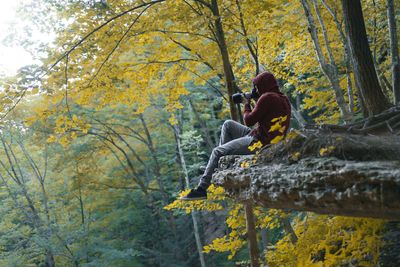 Rear view of man sitting in forest during autumn