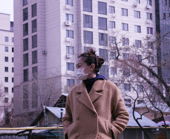 Woman standing by buildings in city during winter