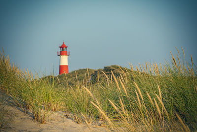 Lighthouse on beach against clear sky