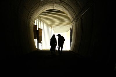 Rear view of silhouette people walking in tunnel