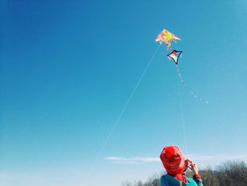 Low angle view of person paragliding against blue sky