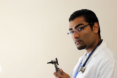 Close-up of young man holding camera over white background