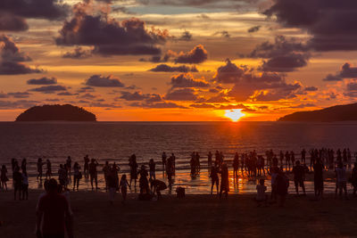 Silhouette people at beach against sky during sunset