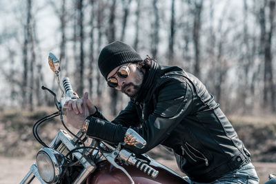 Mid adult man sitting on motorcycle in forest