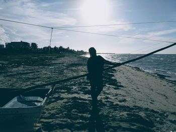 Rear view of man standing on beach against sky