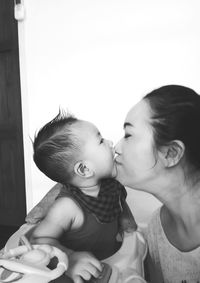 Woman kissing son at home