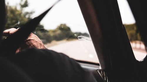 Cropped hand of man smoking cigarette in car