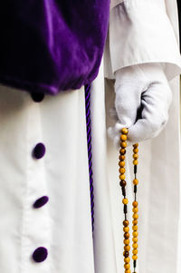 Midsection of man holding rosary