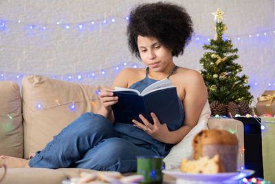 Young woman sitting on sofa in illuminated room