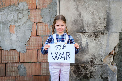 Portrait of girl holding poster against wall