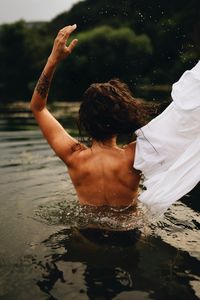 Rear view of shirtless man swimming in lake