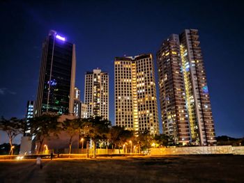 Low angle view of illuminated buildings against sky at night