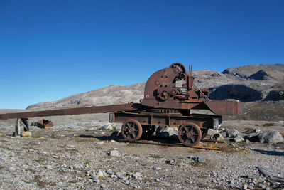 Abandoned truck on field against clear blue sky