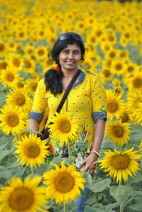 Portrait of woman standing amidst sunflowers on field