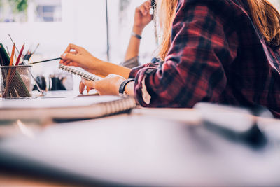 Midsection of woman reading book while sitting at table