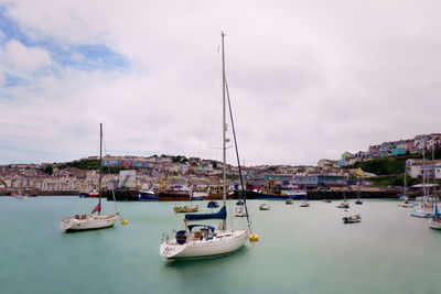 Sailboats moored at harbor against sky