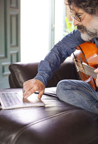 Middle-aged man taking guitar lessons at home.