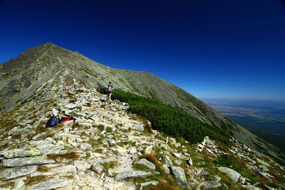 Low angle view of people on mountain against clear sky